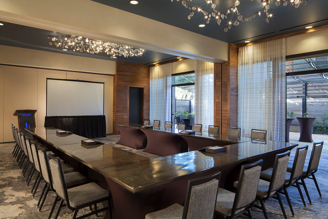 A large meeting room with a long table, chairs, and a projector screen