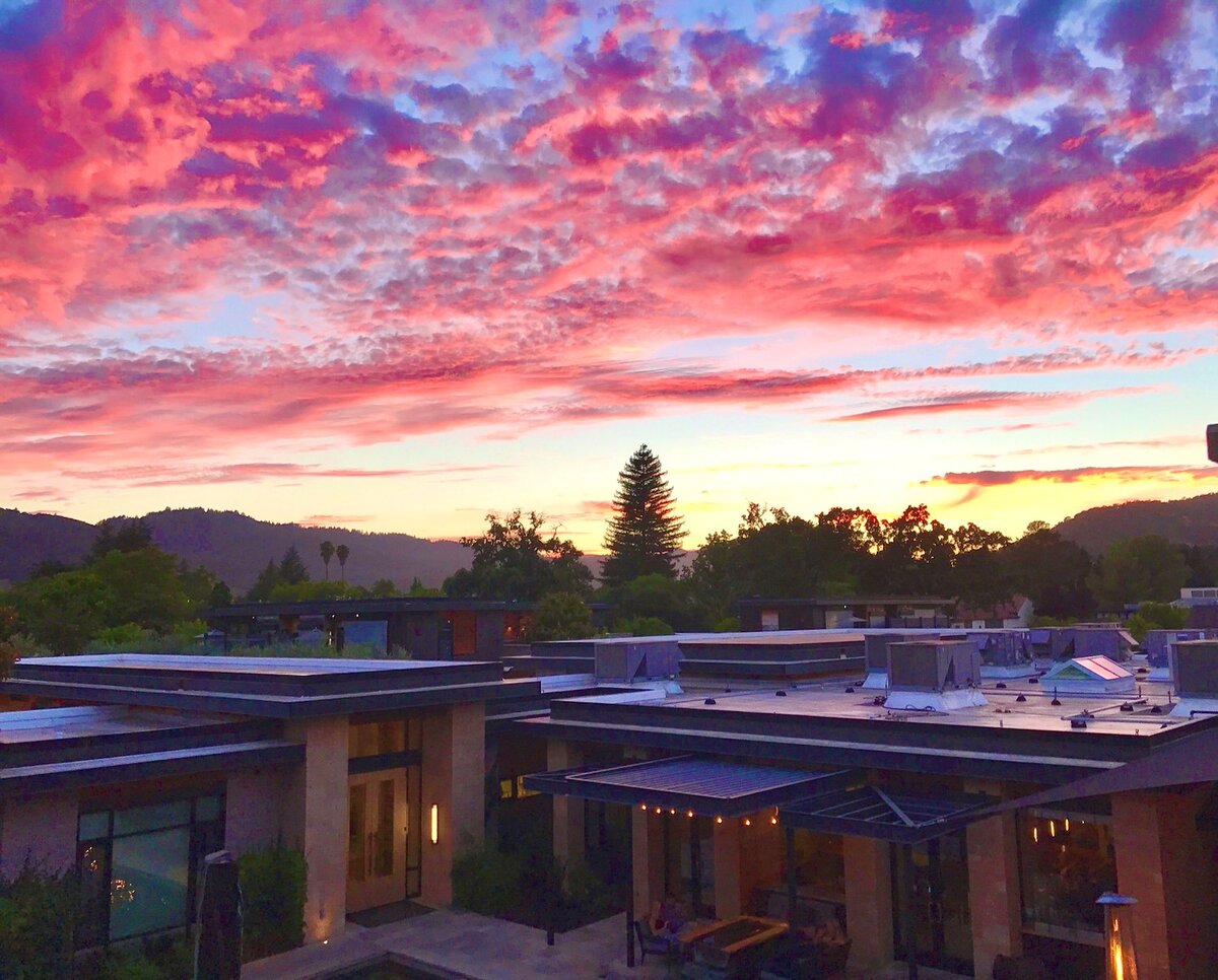 A wide-angle view of a building's exterior with a vibrant sunset in the background.
